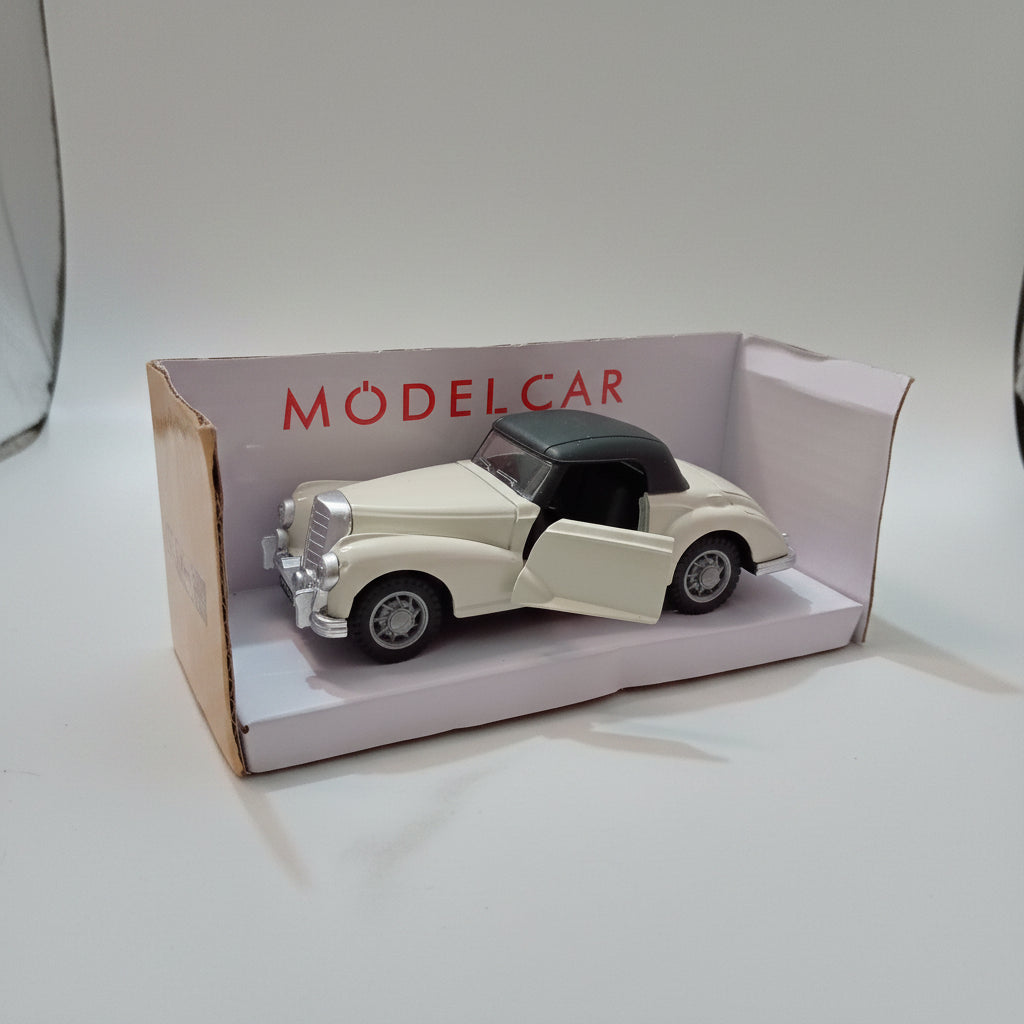 A cream-colored vintage model car with a black convertible top inside its original white packaging box, which features the red 'MODEL CAR' branding.