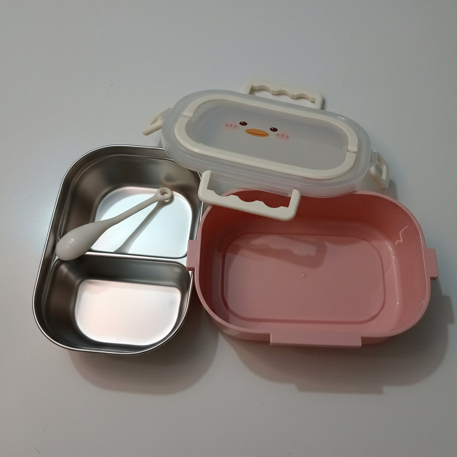 A pink plastic lunch box with a stainless steel divided compartment and a white spoon, shown next to its clear lid with a white handle on a light marble-patterned surface.