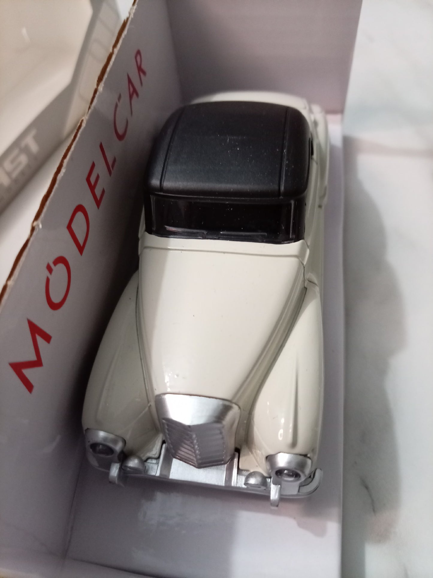A vintage-style model car in cream and black, displayed inside its white retail box with red text reading 'MODEL CAR'.